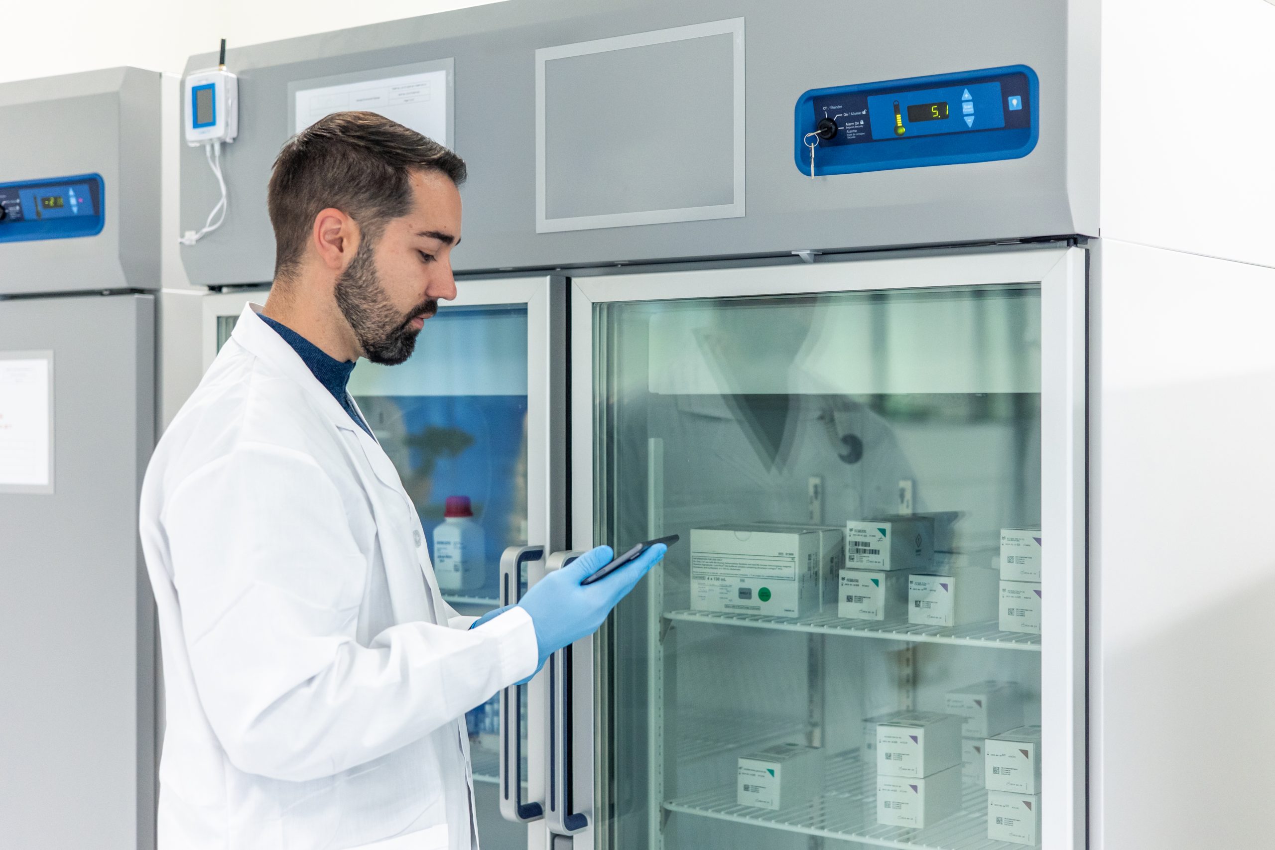 Científico verificando medicamentos refrigerados con tablet
